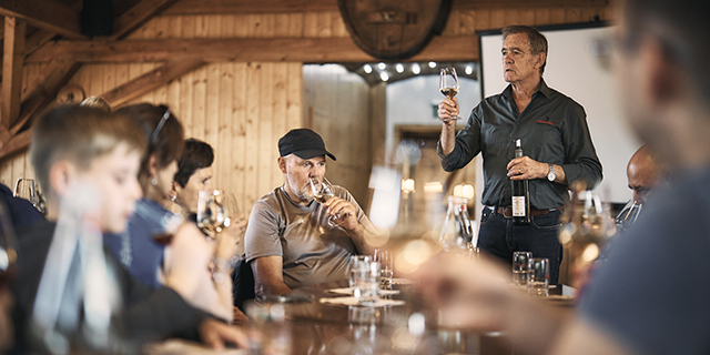 Eine Gruppe von Personen nimmt an einer Weinprobe in einem rustikalen Holzzimmer teil.