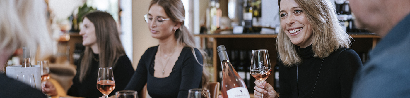 Vier Personen sitzen an einem Tisch und genießen ein Glas Roséwein in einer ungezwungenen Umgebung.