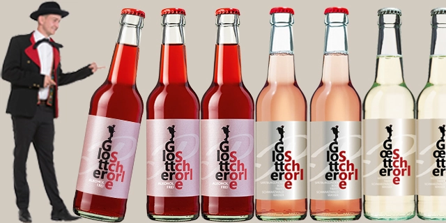 Sechs Flaschen Rosé und Weißwein, links davon steht ein Mann in Anzug und Hut. Sechs Flaschen Rosé und Weißwein, links davon steht ein Mann in Anzug und Hut.